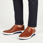 Men's perforated lace up derby shoes in brown, worn with tailored trousers