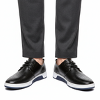 Men's perforated lace up derby shoes in black, worn with tailored trousers